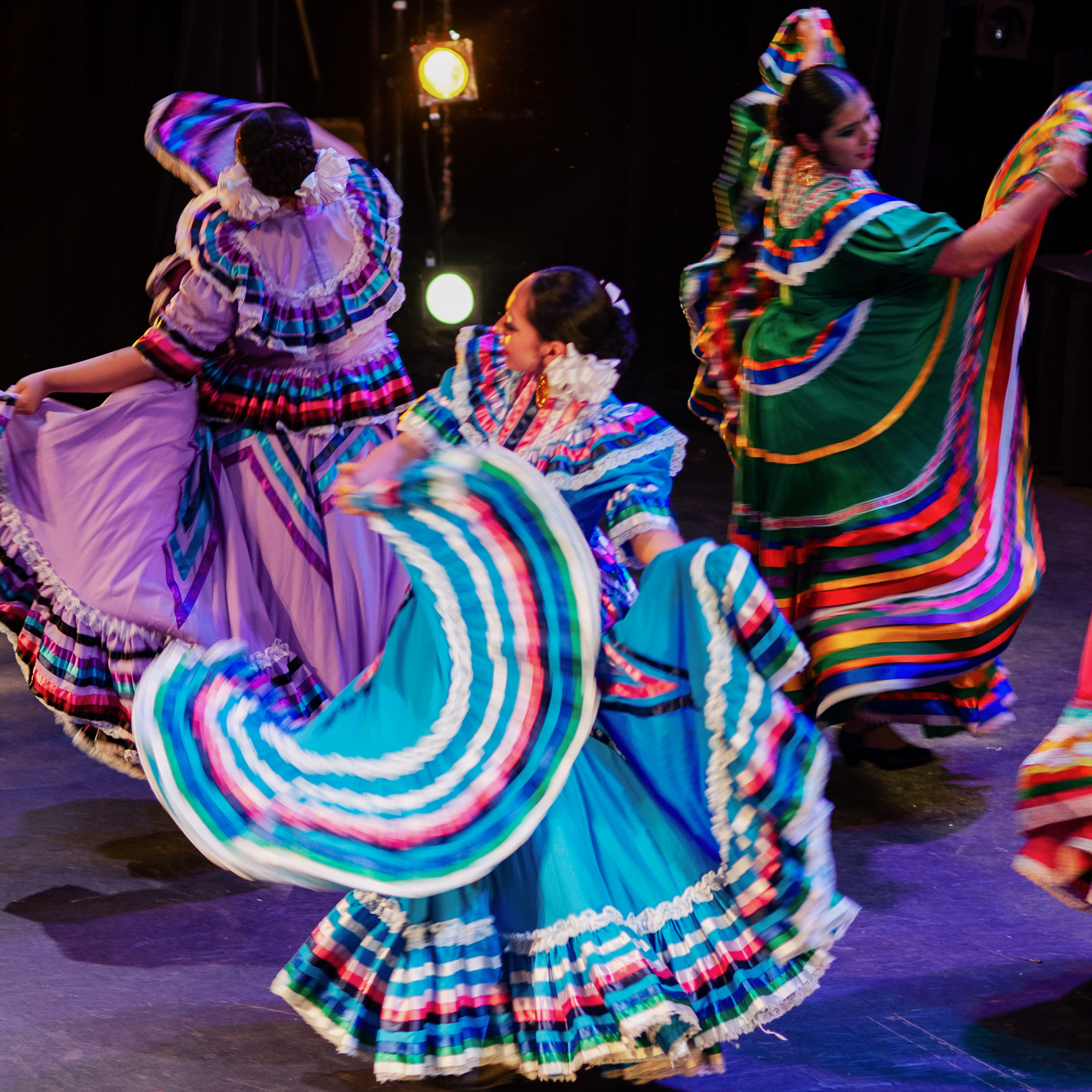 Three girls twirl their skirts in a dance from Jalisco