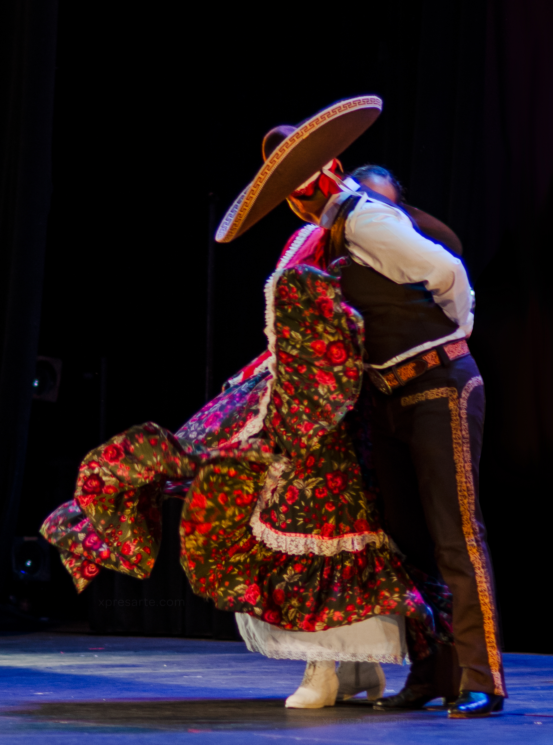 A Mexican Charro leans in to pretend kiss a Mexican girl as her skirt floats in the air at the end of a dance number